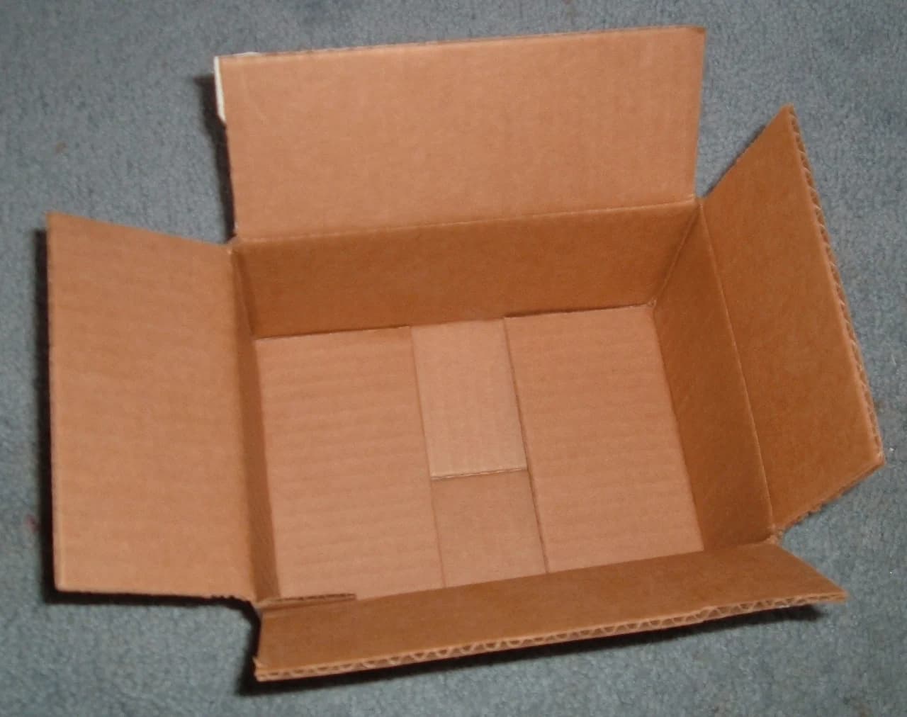 An open brown corrugated cardboard box with its flaps unfolded.